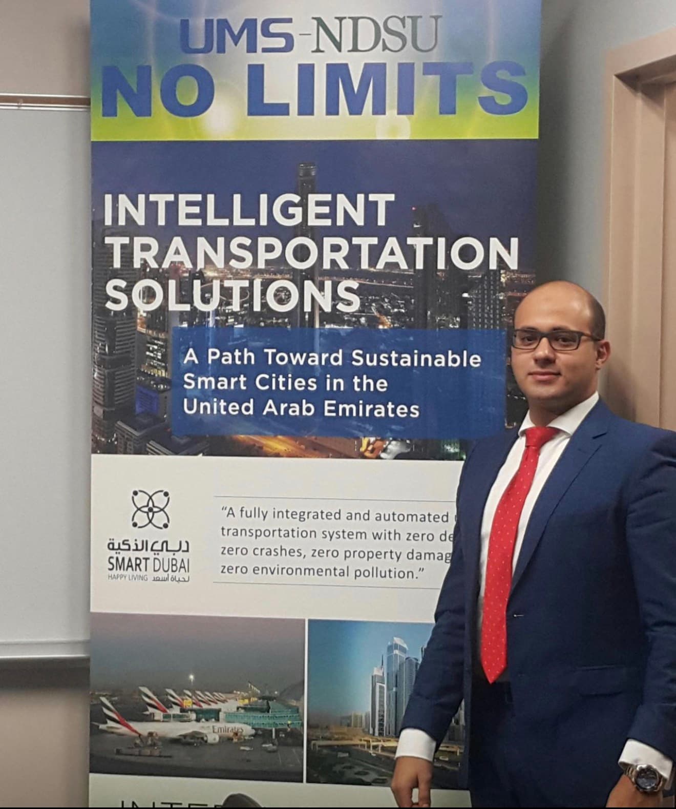 Mohammad Elmoshnib beside a banner reading UMS-NDSU No Limits, Intelligent Transportation Solutions